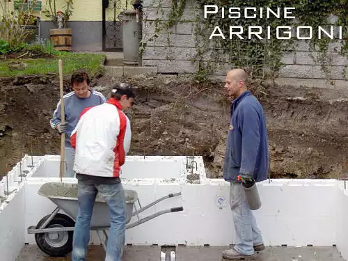 Tre persone intente a riempire le pareti con del cemento